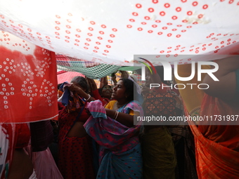 Hindu devotees hold up clothes to receive rice as offerings distributed by the temple authority on the occasion of the Annakut festival in K...