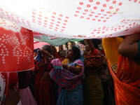 Hindu devotees hold up clothes to receive rice as offerings distributed by the temple authority on the occasion of the Annakut festival in K...