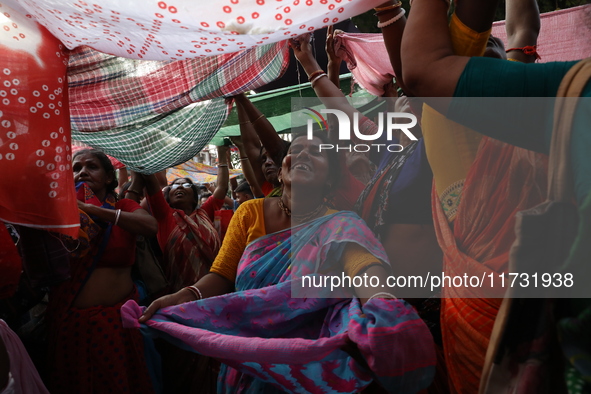 Hindu devotees hold up clothes to receive rice as offerings distributed by the temple authority on the occasion of the Annakut festival in K...