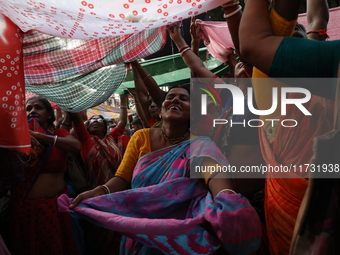 Hindu devotees hold up clothes to receive rice as offerings distributed by the temple authority on the occasion of the Annakut festival in K...