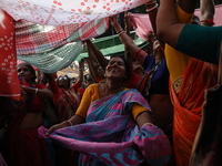 Hindu devotees hold up clothes to receive rice as offerings distributed by the temple authority on the occasion of the Annakut festival in K...