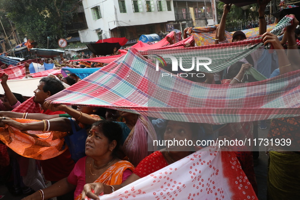 Hindu devotees hold up clothes to receive rice as offerings distributed by the temple authority on the occasion of the Annakut festival in K...