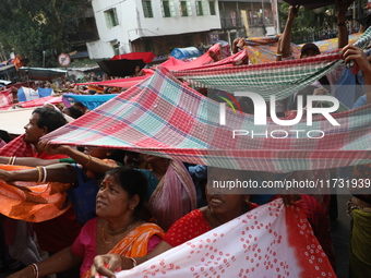 Hindu devotees hold up clothes to receive rice as offerings distributed by the temple authority on the occasion of the Annakut festival in K...