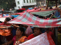 Hindu devotees hold up clothes to receive rice as offerings distributed by the temple authority on the occasion of the Annakut festival in K...