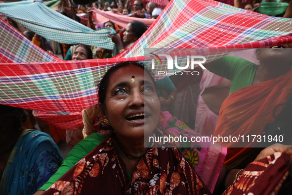 Hindu devotees hold up clothes to receive rice as offerings distributed by the temple authority on the occasion of the Annakut festival in K...