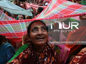 Hindu devotees hold up clothes to receive rice as offerings distributed by the temple authority on the occasion of the Annakut festival in K...