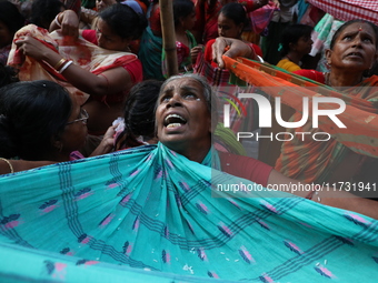 Hindu devotees hold up clothes to receive rice as offerings distributed by the temple authority on the occasion of the Annakut festival in K...