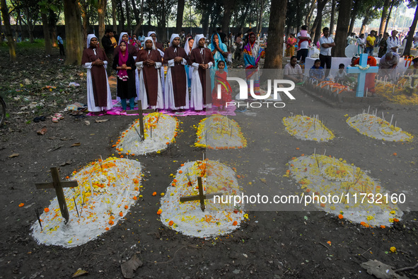 Sisters of Missionaries of Charity pray in front of graves during All Souls' Day observance at a cemetery 80 kilometers outside Kolkata, Ind...