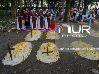 Sisters of Missionaries of Charity pray in front of graves during All Souls' Day observance at a cemetery 80 kilometers outside Kolkata, Ind...