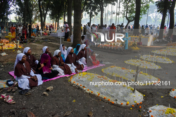 Sisters of Missionaries of Charity pray in front of graves during All Souls' Day observance at a cemetery 80 kilometers outside Kolkata, Ind...