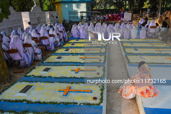 Sisters of Missionaries of Charity pray in front of graves during All Souls' Day observance at a cemetery 80 kilometers outside Kolkata, Ind...