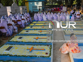 Sisters of Missionaries of Charity pray in front of graves during All Souls' Day observance at a cemetery 80 kilometers outside Kolkata, Ind...