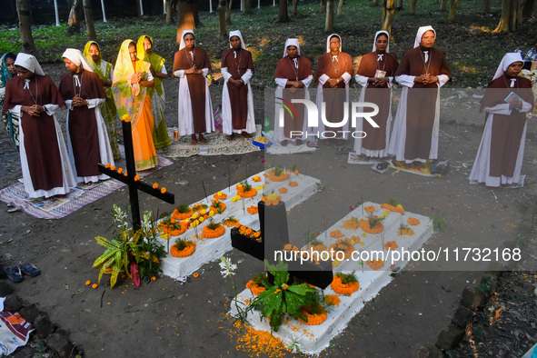 Sisters of Missionaries of Charity pray in front of graves during All Souls' Day observance at a cemetery 80 kilometers outside Kolkata, Ind...