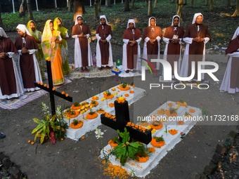 Sisters of Missionaries of Charity pray in front of graves during All Souls' Day observance at a cemetery 80 kilometers outside Kolkata, Ind...