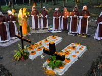 Sisters of Missionaries of Charity pray in front of graves during All Souls' Day observance at a cemetery 80 kilometers outside Kolkata, Ind...