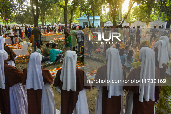 Sisters of Missionaries of Charity pray in front of graves during All Souls' Day observance at a cemetery 80 kilometers outside Kolkata, Ind...