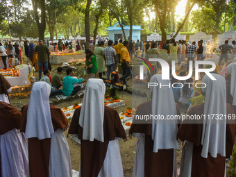 Sisters of Missionaries of Charity pray in front of graves during All Souls' Day observance at a cemetery 80 kilometers outside Kolkata, Ind...