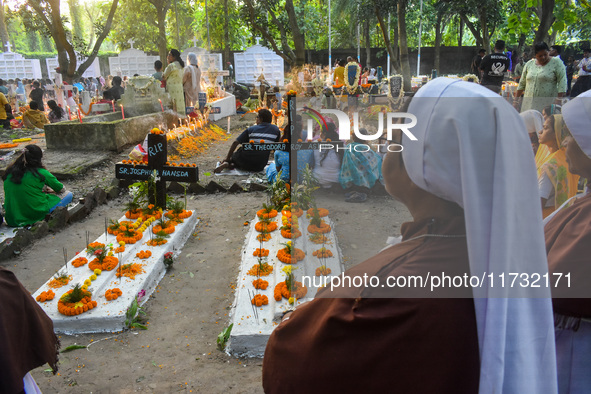 Sisters of Missionaries of Charity pray in front of graves during All Souls' Day observance at a cemetery 80 kilometers outside Kolkata, Ind...