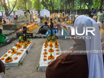 Sisters of Missionaries of Charity pray in front of graves during All Souls' Day observance at a cemetery 80 kilometers outside Kolkata, Ind...