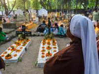 Sisters of Missionaries of Charity pray in front of graves during All Souls' Day observance at a cemetery 80 kilometers outside Kolkata, Ind...