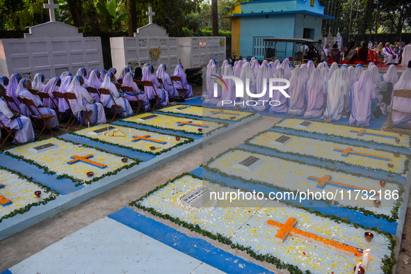 Sisters of Missionaries of Charity pray in front of graves during All Souls' Day observance at a cemetery 80 kilometers outside Kolkata, Ind...