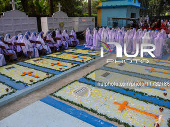 Sisters of Missionaries of Charity pray in front of graves during All Souls' Day observance at a cemetery 80 kilometers outside Kolkata, Ind...