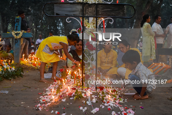 A boy lights candles over the grave of his relative during All Souls' Day observance at a cemetery 80 kilometers outside Kolkata, India, on...