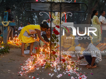 A boy lights candles over the grave of his relative during All Souls' Day observance at a cemetery 80 kilometers outside Kolkata, India, on...