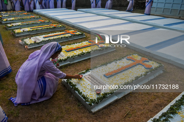 A sister of the Missionaries of Charity lights candles over a grave during All Souls' Day observance at a cemetery 80 kilometers outside Kol...