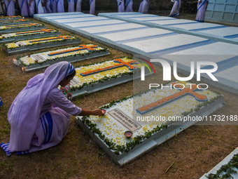 A sister of the Missionaries of Charity lights candles over a grave during All Souls' Day observance at a cemetery 80 kilometers outside Kol...