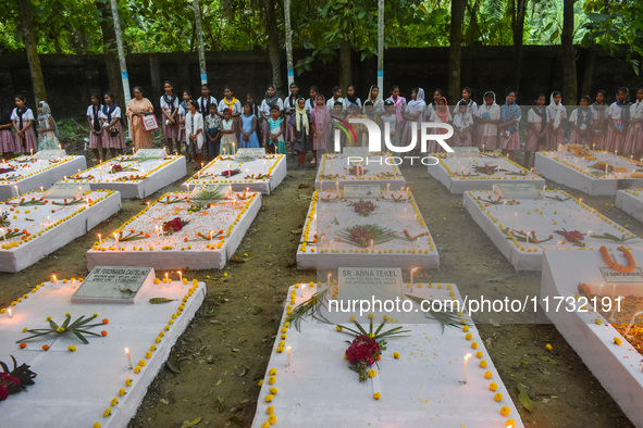 Sisters of Missionaries of Charity and children pray in front of graves during All Souls' Day observance at a cemetery 80 kilometers outside...