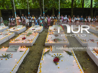 Sisters of Missionaries of Charity and children pray in front of graves during All Souls' Day observance at a cemetery 80 kilometers outside...