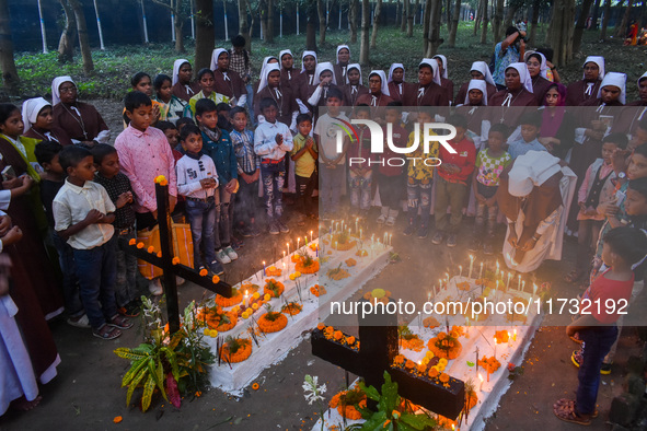 Sisters of Missionaries of Charity and children pray in front of graves during All Souls' Day observance at a cemetery 80 kilometers outside...