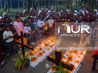 Sisters of Missionaries of Charity and children pray in front of graves during All Souls' Day observance at a cemetery 80 kilometers outside...