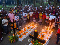 Sisters of Missionaries of Charity and children pray in front of graves during All Souls' Day observance at a cemetery 80 kilometers outside...