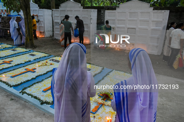 Sisters of Missionaries of Charity pray in front of graves during All Souls' Day observance at a cemetery 80 kilometers outside Kolkata, Ind...