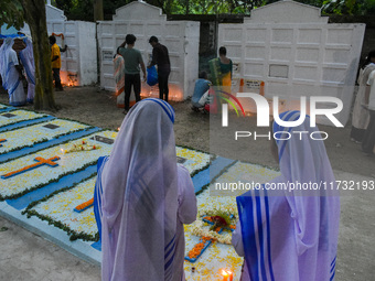 Sisters of Missionaries of Charity pray in front of graves during All Souls' Day observance at a cemetery 80 kilometers outside Kolkata, Ind...