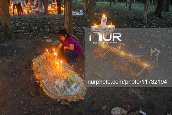 A little girl lights candles over her relative's grave during All Souls' Day observance at a cemetery 80 kilometers outside Kolkata, India,...