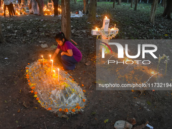 A little girl lights candles over her relative's grave during All Souls' Day observance at a cemetery 80 kilometers outside Kolkata, India,...