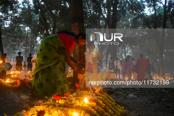 A mother and child light candles over her relative's grave during All Souls Day observance at a cemetery 80 kilometers outside of Kolkata, I...