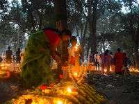 A mother and child light candles over her relative's grave during All Souls Day observance at a cemetery 80 kilometers outside of Kolkata, I...