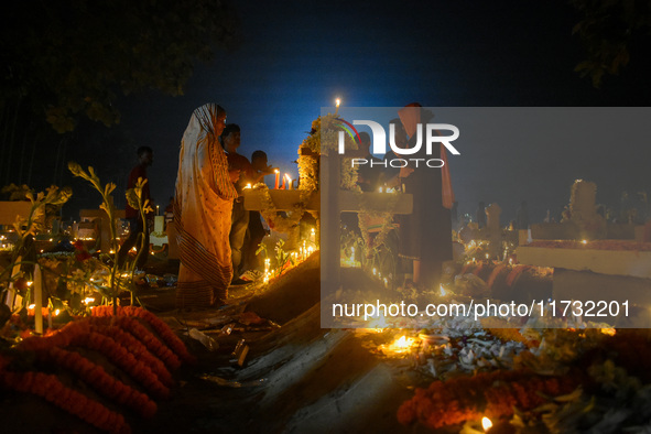 A family prays in front of their relative's grave during All Souls' Day observance at a cemetery 80 kilometers outside Kolkata, India, on No...