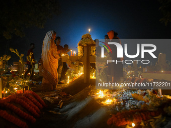 A family prays in front of their relative's grave during All Souls' Day observance at a cemetery 80 kilometers outside Kolkata, India, on No...