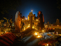 A family prays in front of their relative's grave during All Souls' Day observance at a cemetery 80 kilometers outside Kolkata, India, on No...