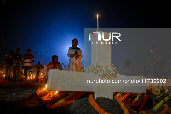 A girl prays in front of her relative's grave during All Souls' Day observance at a cemetery 80 kilometers outside Kolkata, India, on Novemb...