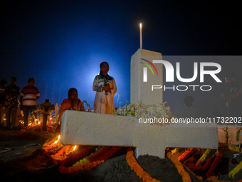 A girl prays in front of her relative's grave during All Souls' Day observance at a cemetery 80 kilometers outside Kolkata, India, on Novemb...