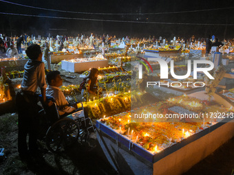 A man in a wheelchair is in front of the grave of his relative during All Souls' Day observance at a cemetery 80 kilometers outside Kolkata,...