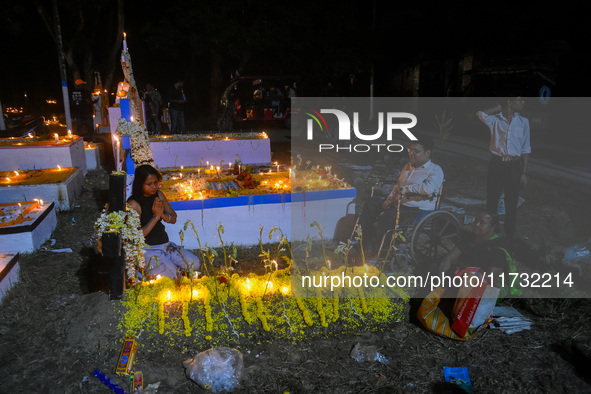 A man in a wheelchair is in front of the grave of his relative during All Souls' Day observance at a cemetery 80 kilometers outside Kolkata,...