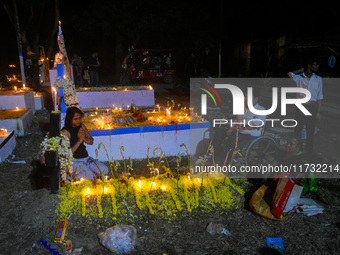 A man in a wheelchair is in front of the grave of his relative during All Souls' Day observance at a cemetery 80 kilometers outside Kolkata,...