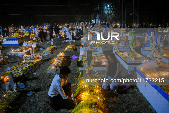 A family lights candles over their relative's grave during All Souls' Day observance at a cemetery 80 kilometers outside Kolkata, India, on...